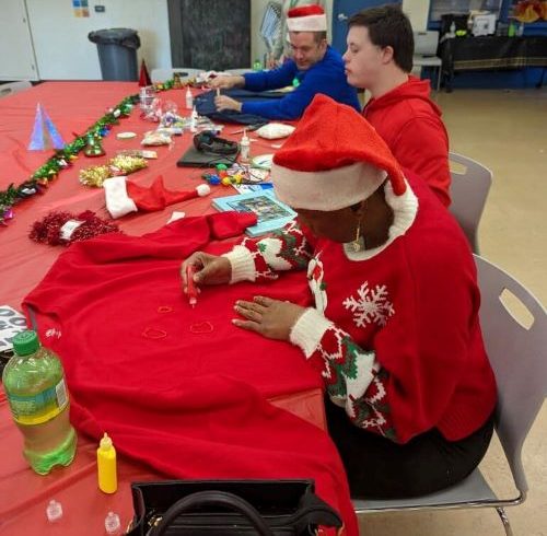 Participants decorating their ugly sweaters at a party.