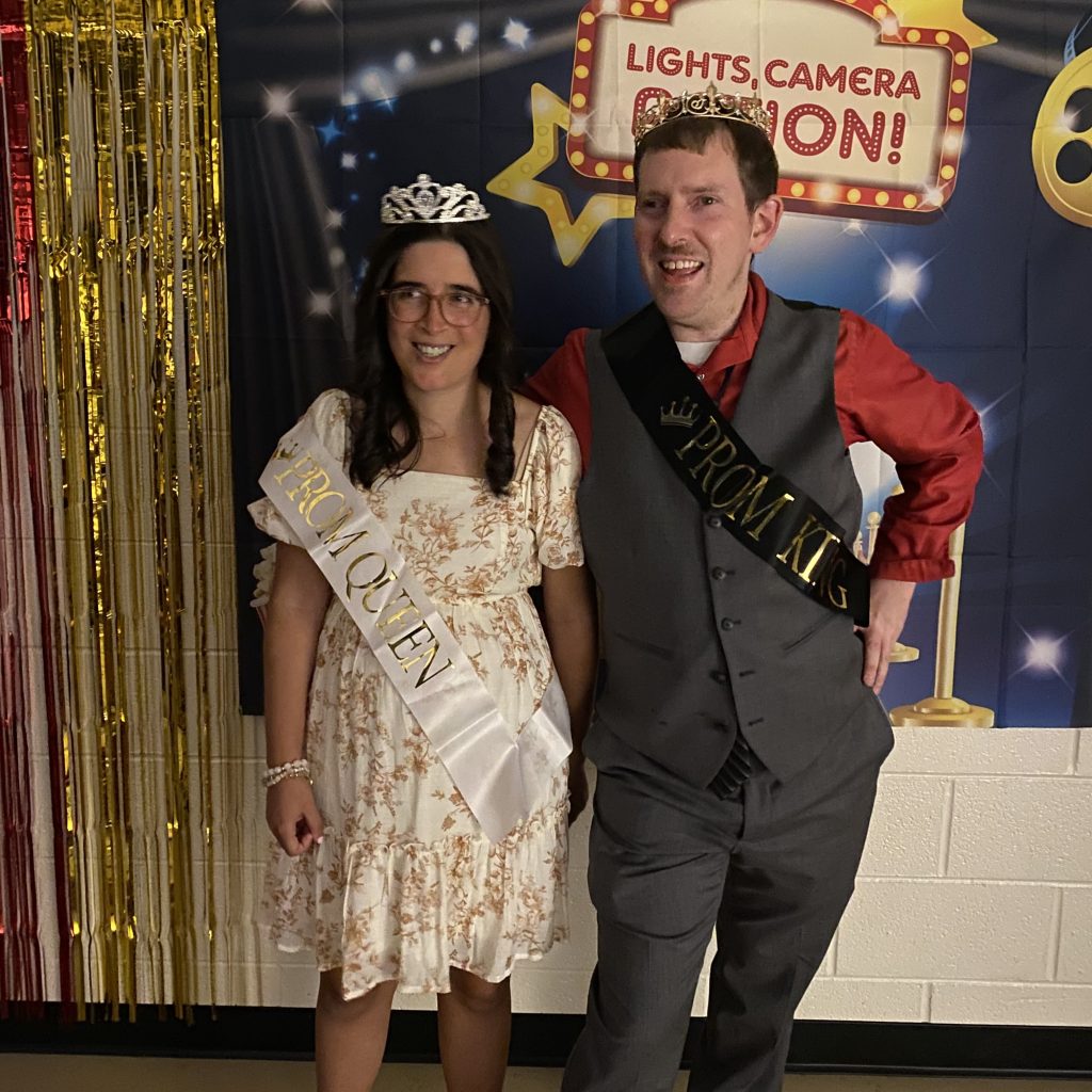 A man and woman in a prom sash and crown.
