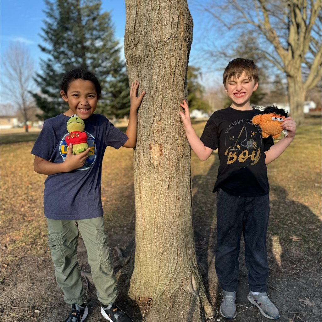 Two boys standing by a tree