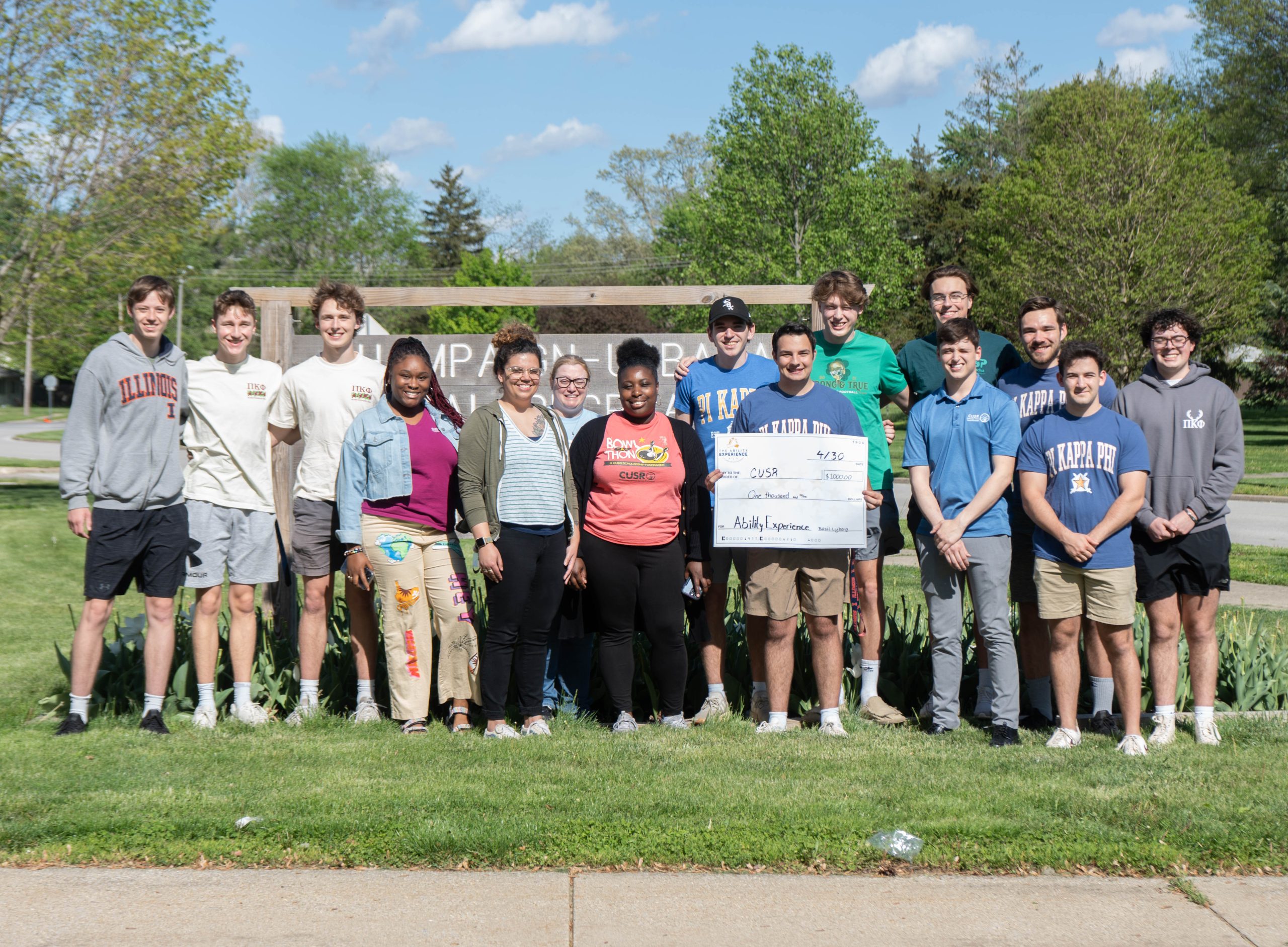 Group photo of CUSR staff and UIUC fraternity members holding check for $1,000
